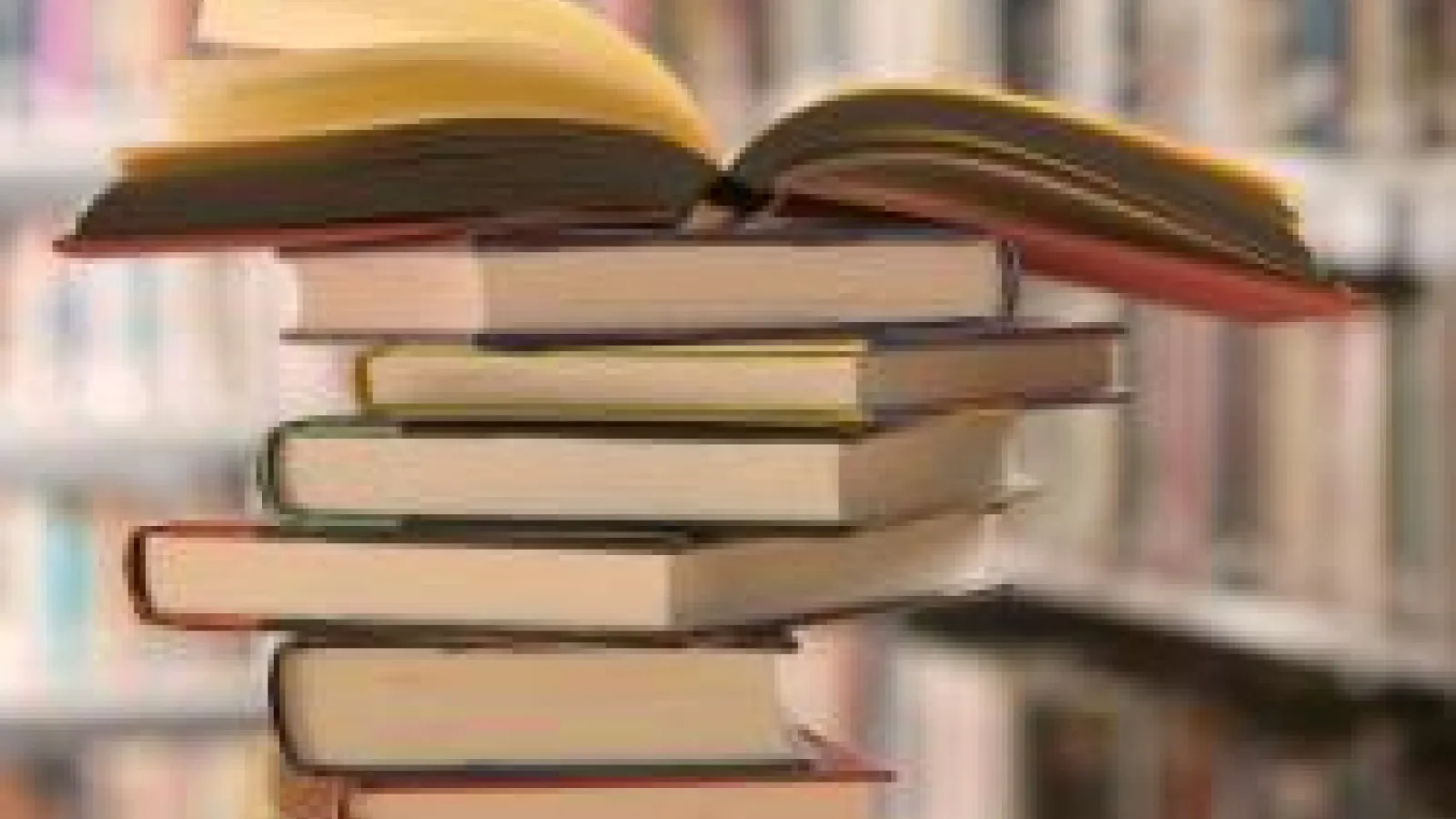A stack of books, with the top book lying open