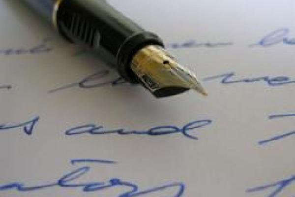 A fountain pen lies on a page of handwritten text